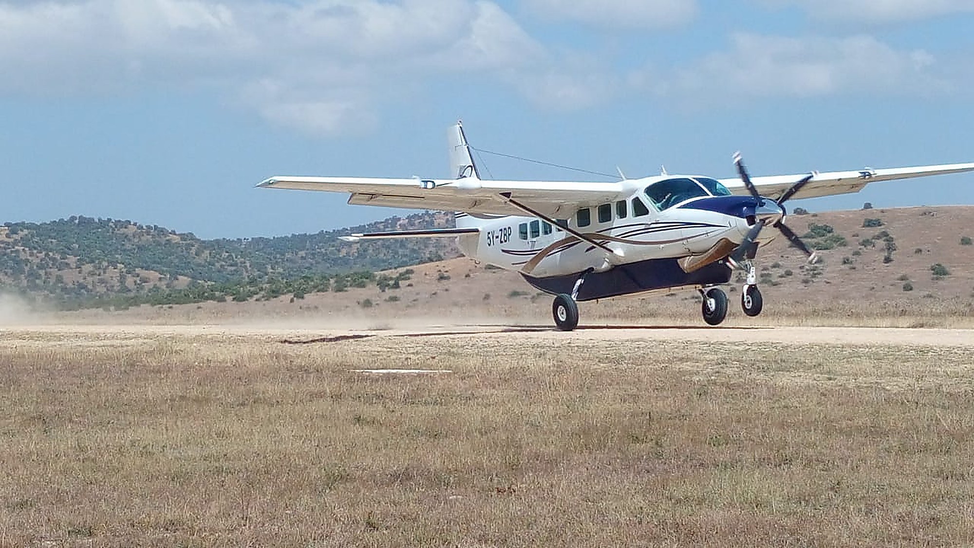 A bush plane on a dirt airstrip, grass and scrub either side